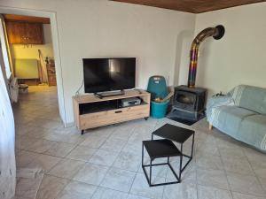 a living room with a flat screen tv and a wood stove at La cabane de Claude in Fougerolles