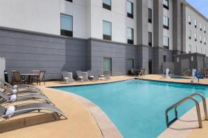 ein Hotelpool mit Stühlen und einem Tisch und ein Gebäude in der Unterkunft Hampton Inn Cotulla in Cotulla
