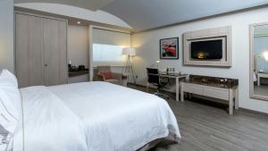 a bedroom with a white bed and a desk and a tv at Holiday Inn Express Mexico- Toreo by IHG in Mexico City +72 photos