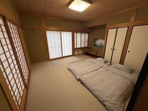 a bedroom with a large bed in a room with windows at Anan Seaside House in Anan