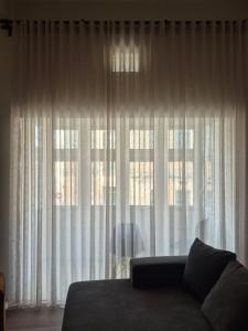 a couch in front of a window with white curtains at Modern Designer Apartment Private Yard in Hamrun