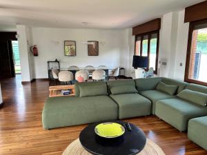 a living room with a green couch and a table at Ecopausa Somió - Gijón in Gijón