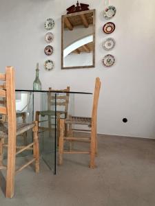 a glass table with chairs and a mirror and plates on the wall at Kamara since 1900 in Archangelos