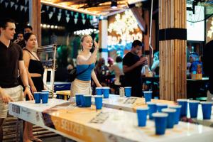 a woman standing in front of a table with blue cups at Sea Beach Hostel & Club Beachfront 18-39 years only in Ao Nang Beach