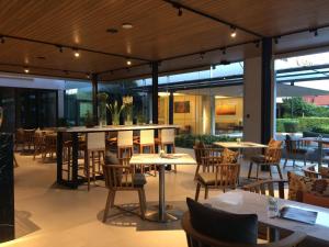 a restaurant with tables and chairs and windows at Bangna Pride Hotel & Residence in Bangkok