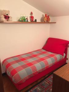 a bed with a red and blue plaid blanket in a room at Appartamento Bernasconi in Madesimo
