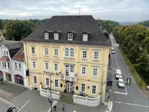 a large yellow building with a black roof on a street at Hotel Lippischer Hof in Detmold
