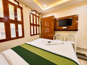 a bedroom with a bed with a tv on the wall at Hotel R GUEST HOUSE - NEAR KASHI VISHWANATH TEMPLE in Varanasi