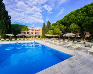 una gran piscina con sillas y sombrillas en Hotel Club Lacona, en Lacona