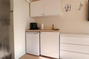 a kitchen with white cabinets and a refrigerator at MoselStudio Briedel - Sonnenterrasse und Komfort in Briedel