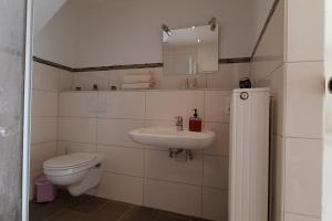 a white bathroom with a toilet and a sink at MoselStudio Briedel - Sonnenterrasse und Komfort in Briedel
