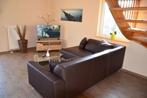 a living room with a leather couch and a television at Bella Casa 35 in Juliusruh