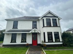 a white house with a red door at Strandhill Guesthouse in Sligo