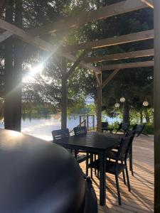 a wooden table and chairs on a deck with a lake at Private Riverside Cabin, Utajärvi in Korhola