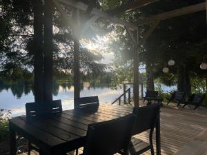 a wooden table and chairs on a deck with a lake at Private Riverside Cabin, Utajärvi in Korhola +21 photos