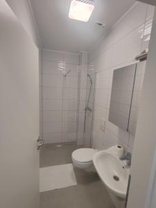 a white bathroom with a toilet and a sink at Hotel Jelena in Brnaze +14 photos