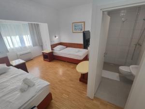a bedroom with two beds and a bathroom with a shower at Hotel Jelena in Brnaze