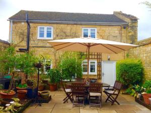 a table and chairs under an umbrella in a garden at Troy House in Painswick