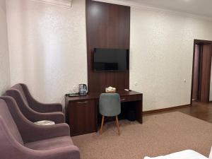 a room with a desk and two chairs and a television at Grand Turon Plaza Hotel in Tashkent