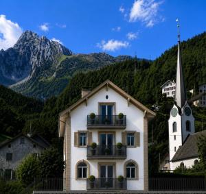 a white building with a church and a mountain at Lake House in Mühlehorn
