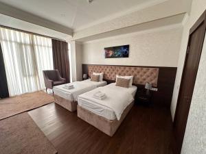 a hotel room with two beds and a chair at Grand Turon Plaza Hotel in Tashkent +15 photos