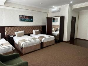 a hotel room with two beds and a mirror at Grand Turon Plaza Hotel in Tashkent