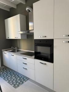 a kitchen with white cabinets and a black oven at Les Maisons Manzoni in Magenta