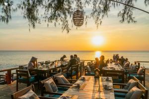 people sitting at tables on the beach at sunset at Camia Resort & Spa in Phú Quốc