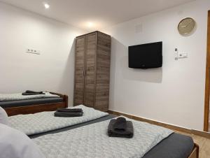a bedroom with two beds and a flat screen tv at Oázis Apartman in Sárospatak