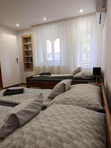 a room with three beds and a window at Oázis Apartman in Sárospatak