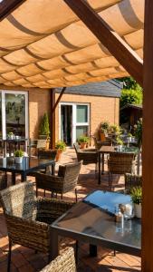 a patio with tables and chairs under a wooden umbrella at Lieth-Hotel-Grünreich in Bad Fallingbostel
