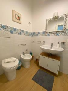 a bathroom with a sink and a toilet and a mirror at Casa Mamà in Marzamemi