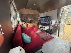 a living room with a red couch in an rv at Tin Can Town Oirschot in Oirschot