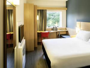 a hotel room with a bed and a desk at ibis Juiz de Fora in Juiz de Fora +70 photos