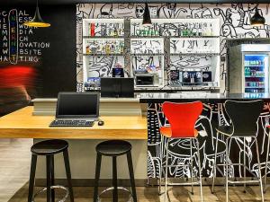 a bar with a laptop computer on a counter with stools at ibis Juiz de Fora in Juiz de Fora
