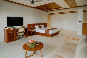a bedroom with a bed and a desk and a tv at Mountree Munnar by Kondody Hotels in Anachal