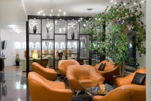 een lobby met oranje stoelen en tafels en planten bij City Hotel Isar-Residenz in Landshut