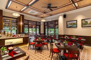 a restaurant with wooden tables and red chairs at Royal Riverside Hoi An Hotel-Newly Renovated & Reopened in Hoi An