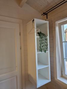 a white book shelf in a room with a plant at AMONG Nature Stay in Vilnius in Vilnius