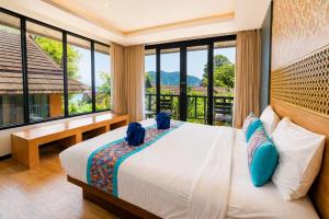 a bedroom with a bed and a balcony with windows at Phi Phi Long Beach Resort & Villa in Phi Phi Islands +36 photos