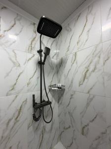 a shower in a bathroom with white marble walls at Kut Hotel in Karakol