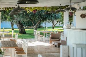 patio ze stołami, krzesłami i drzewem w obiekcie Masseria Don Luigi-Luxury Farmhouse w mieście Savelletri di Fasano