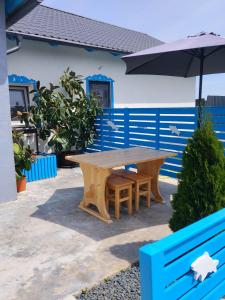 ein Holztisch und eine Bank mit einem Sonnenschirm in der Unterkunft Studio Casa Katiușa in Jurilovca