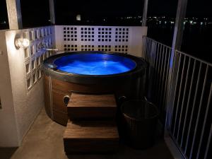 a jacuzzi tub on a balcony at night at 風の音 in Motobu