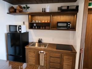 a kitchen with a sink and a black refrigerator at 風の音 in Motobu +14 photos