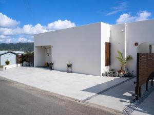 a white house with a large driveway at 風の音 in Motobu
