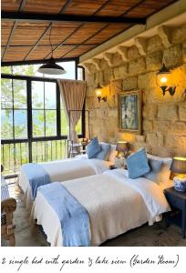 a bedroom with two beds in a stone wall at Laklouk 1808 Lodge by Hansa in ‘Ayn aş Şalīb