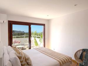 a white bedroom with a bed and a balcony at Can Paola in Sant Josep
