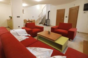 a living room with a red couch and two chairs at Na pasekách u lesa apartmán Radost in Osvětimany