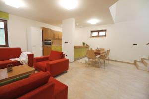a living room with red couches and a table and a kitchen at Na pasekách u lesa apartmán Radost in Osvětimany
